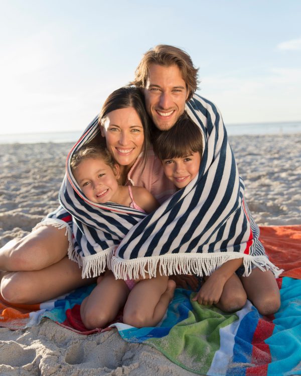 Portrait happy family wrapped in towel on sunny beach